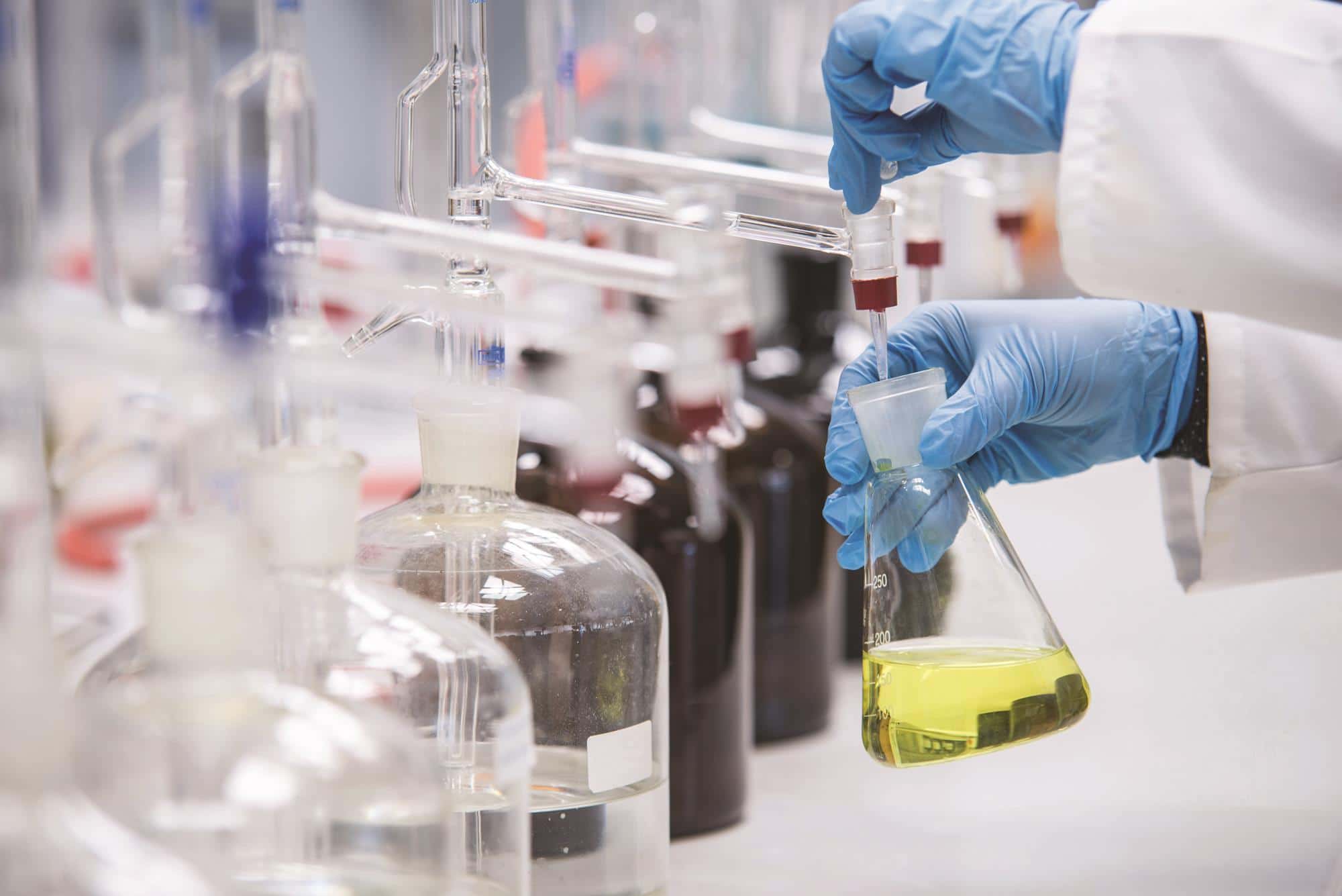 A worker in a laboratory handling chemical liquids in a safe way