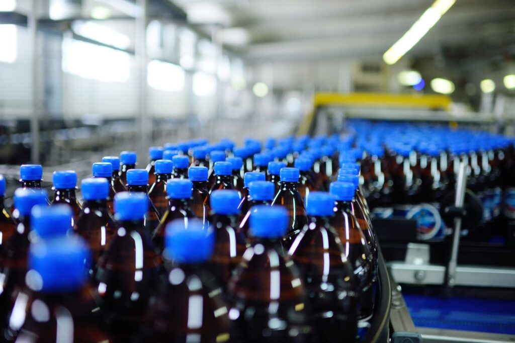 Amber PET soft drink bottles with blue caps moving along a beverage production line