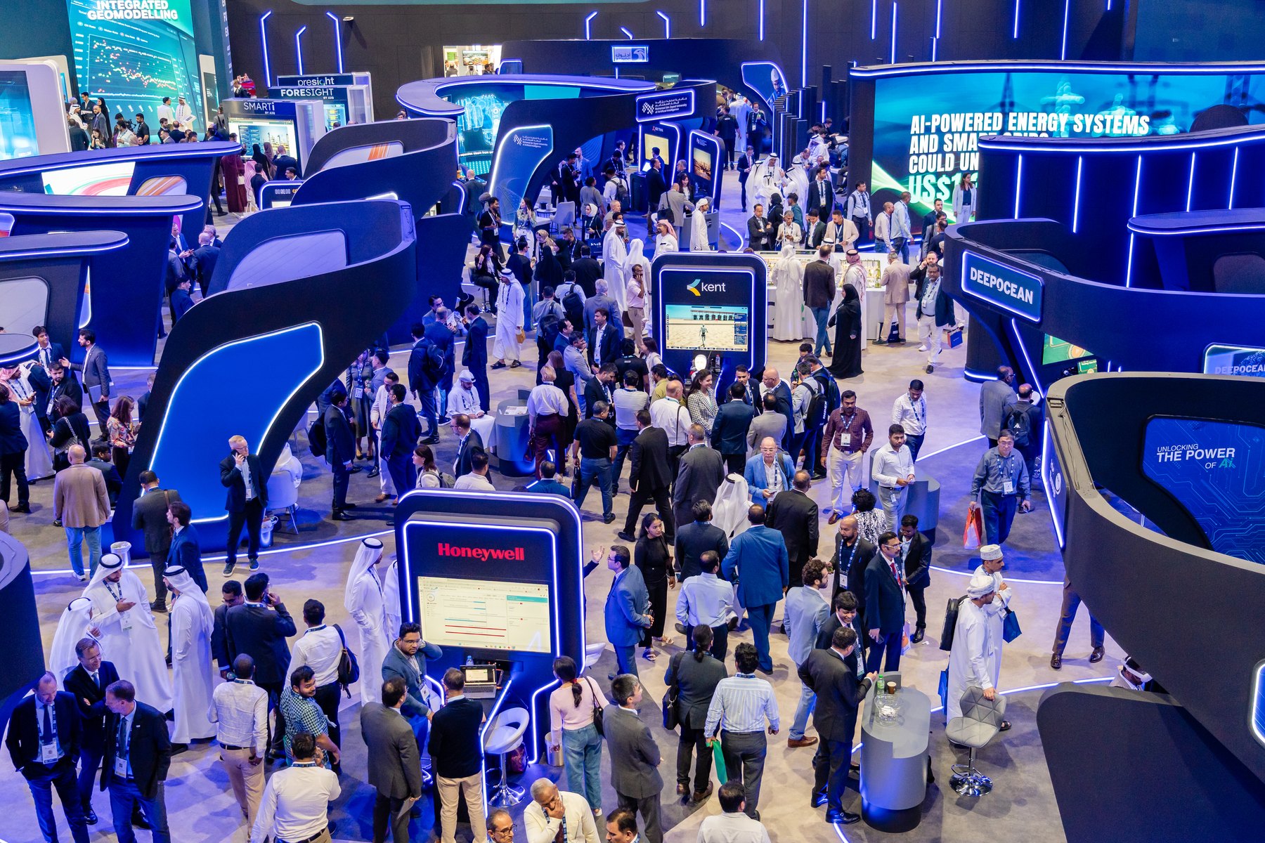 Visitors exploring illuminated technology stands in the AI Zone exhibition hall at ADIPEC