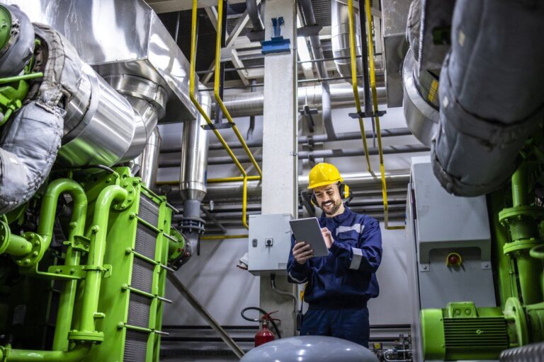 Engineer with a tablet inspecting gas engine equipment in a plant room