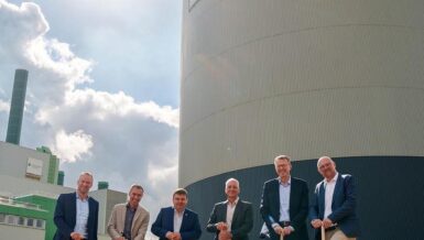 Six men holding spades at the ground-breaking ceremony in front of the Stadtwerke Duisburg heat storage tank at the Wanheim Energy Park