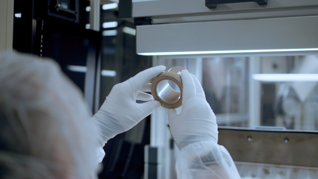 Technician in cleanroom gloves inspecting a SYGEF Ultra PEEK fitting under high-purity production conditions
