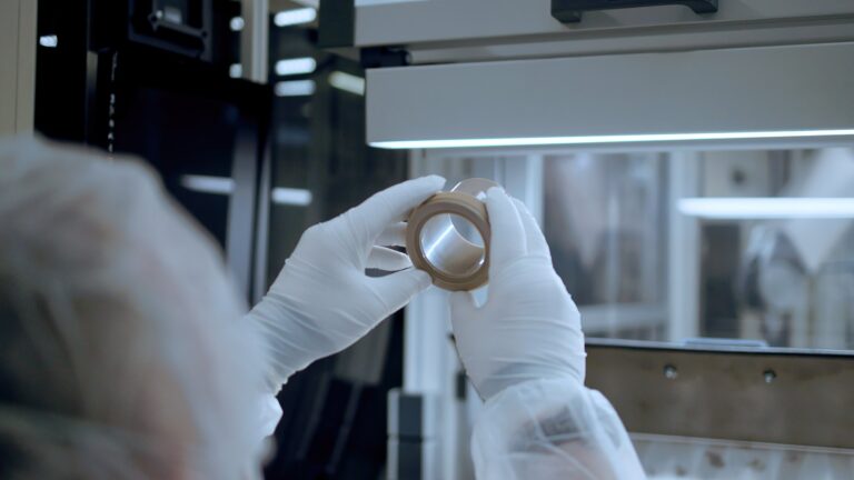 Technician in cleanroom gloves inspecting a SYGEF Ultra PEEK fitting under high-purity production conditions