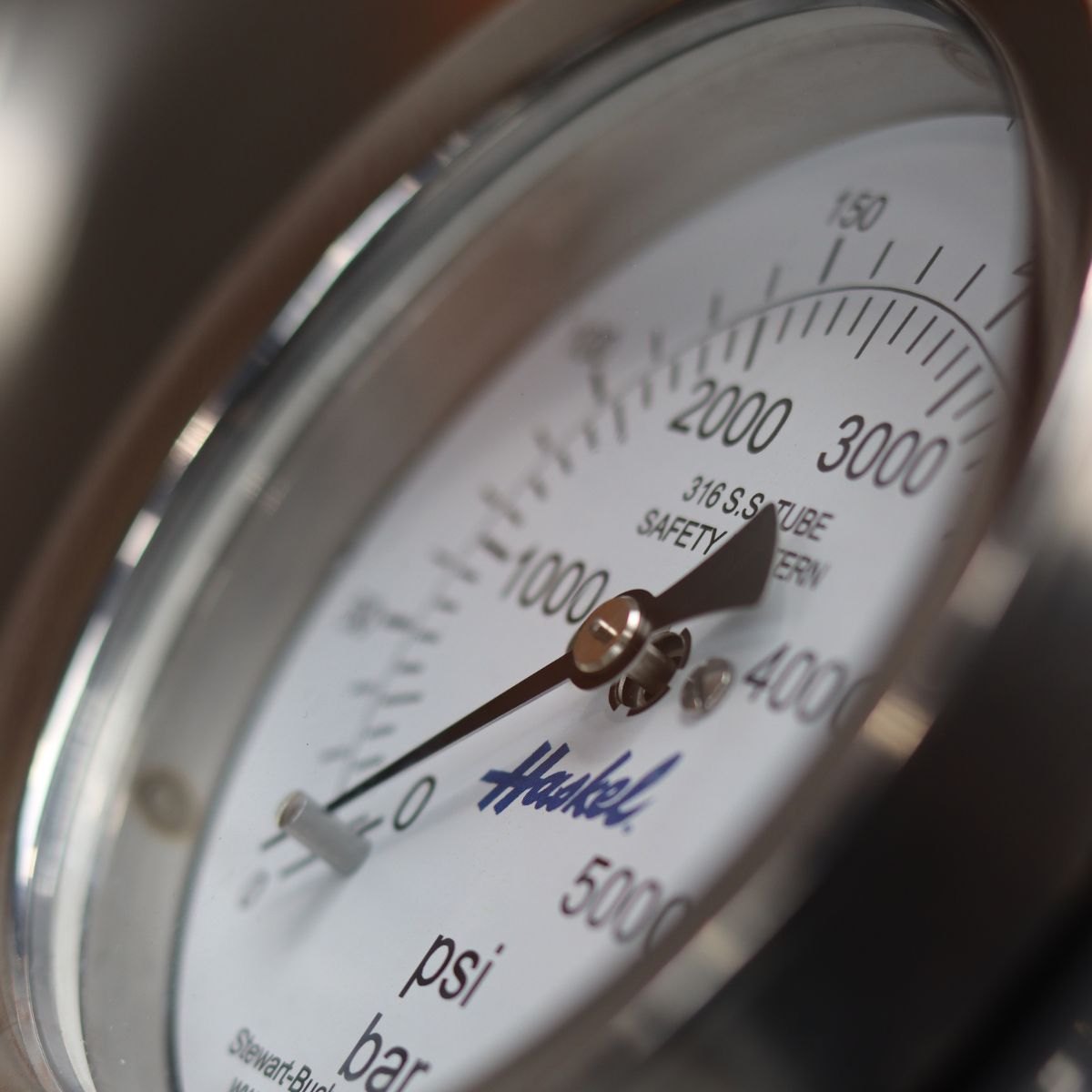 Close-up of a Haskel high-pressure gauge with a 316 stainless steel tube, reading in psi and bar