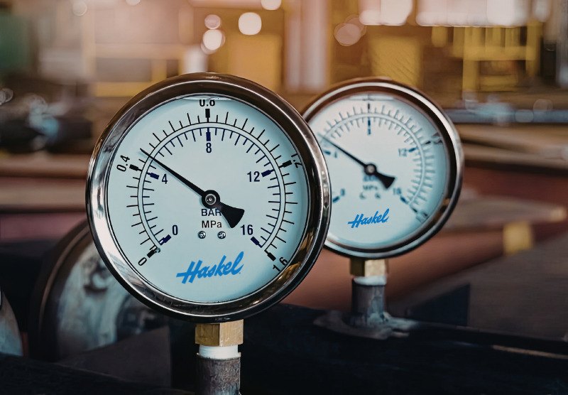 Two Haskel pressure gauges reading in bar and MPa, installed on industrial piping