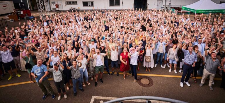Large group of HERMETIC employees cheering together outdoors at the anniversary celebration in Gundelfingen
