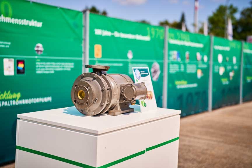 Canned motor pump displayed on a white pedestal in front of green anniversary exhibition walls