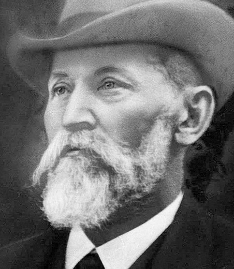 Historic black and white portrait of a bearded man in a wide-brimmed hat