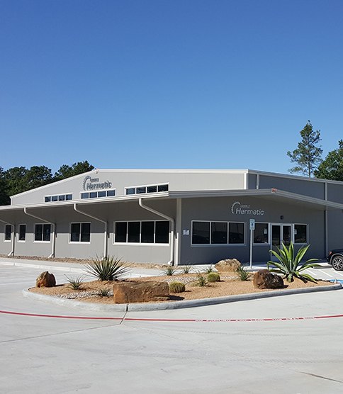 Modern HERMETIC company building with desert landscaping and cacti in Texas