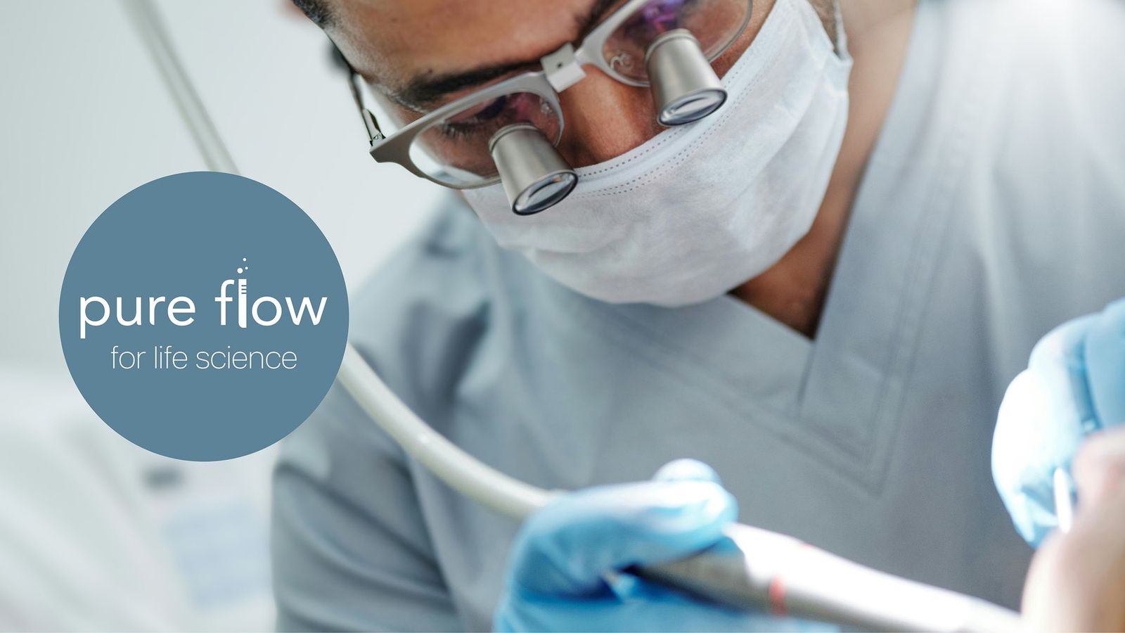 Dentist wearing magnifying loupes treating a patient, with the Pure Flow for life science logo
