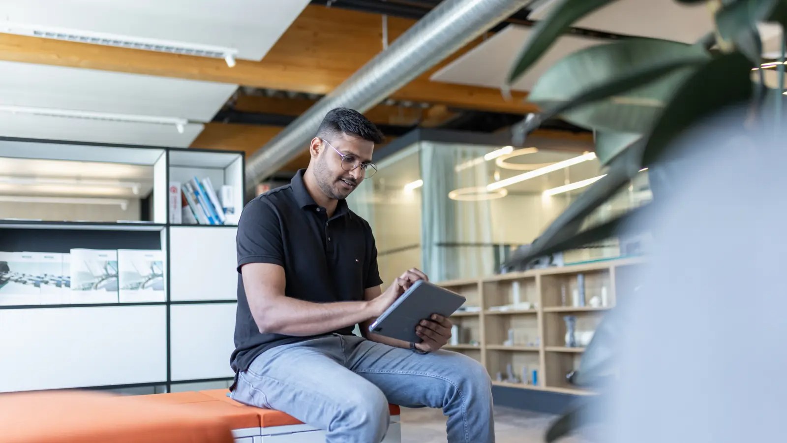 Man in a black polo shirt using a tablet in a modern office