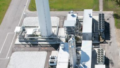 Aerial view of a biogas liquefaction plant with a tall vertical LNG storage tank and process modules