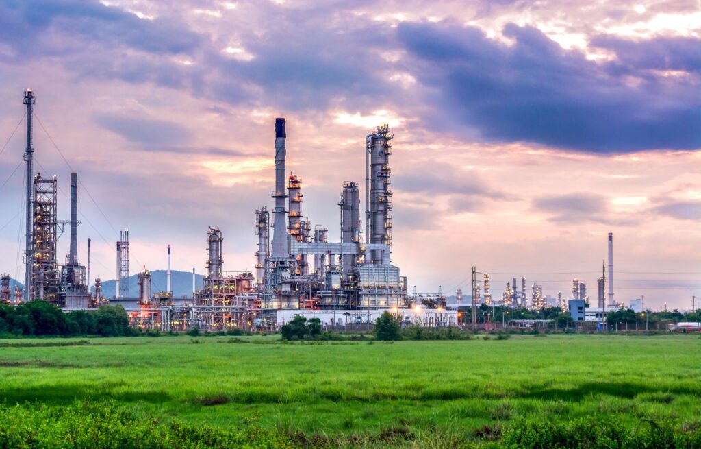 Petrochemical plant with distillation columns and flare stacks under an evening sky