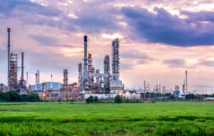 Petrochemical plant with distillation columns and flare stacks under an evening sky