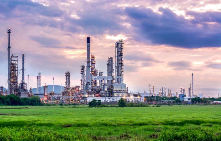Petrochemical plant with distillation columns and flare stacks under an evening sky