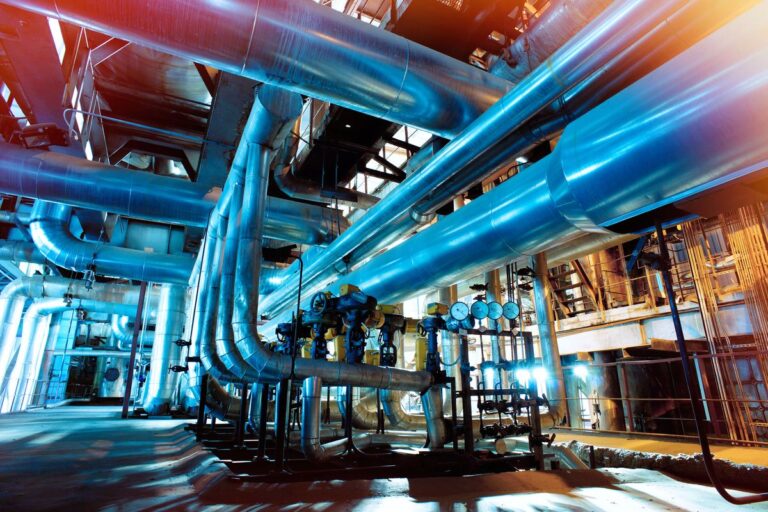 Insulated process piping with valves and pressure gauges in a plant hall
