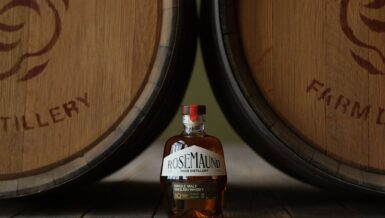 Bottle of Rosemaund 10-year-old single malt English whisky standing between two oak casks