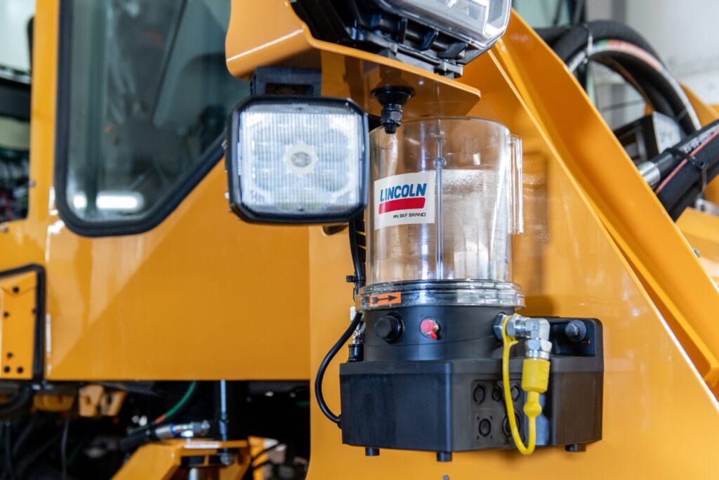 SKF PLP automatic lubrication pump mounted on the frame of a yellow mobile machine