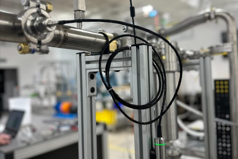 Vaisala DMP dew point probe for moisture measurement in hydrogen, installed inline on a gas line at JTEC Energy with its electronics housing showing a green light