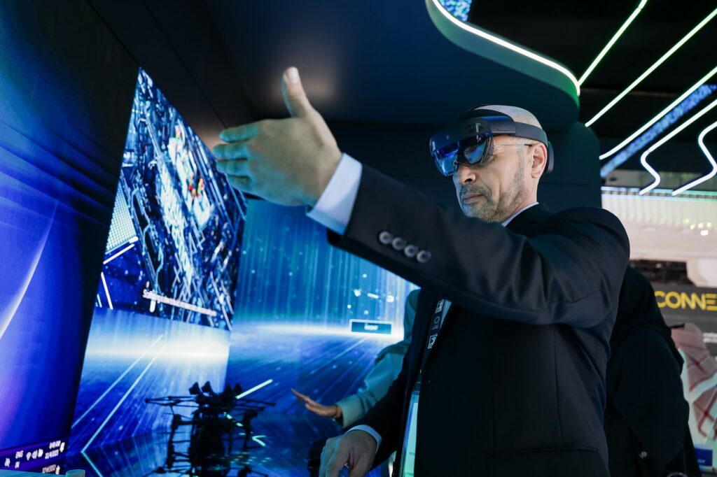 Visitor wearing a mixed-reality headset gestures at a large screen during a technology demonstration at ADIPEC in Abu Dhabi
