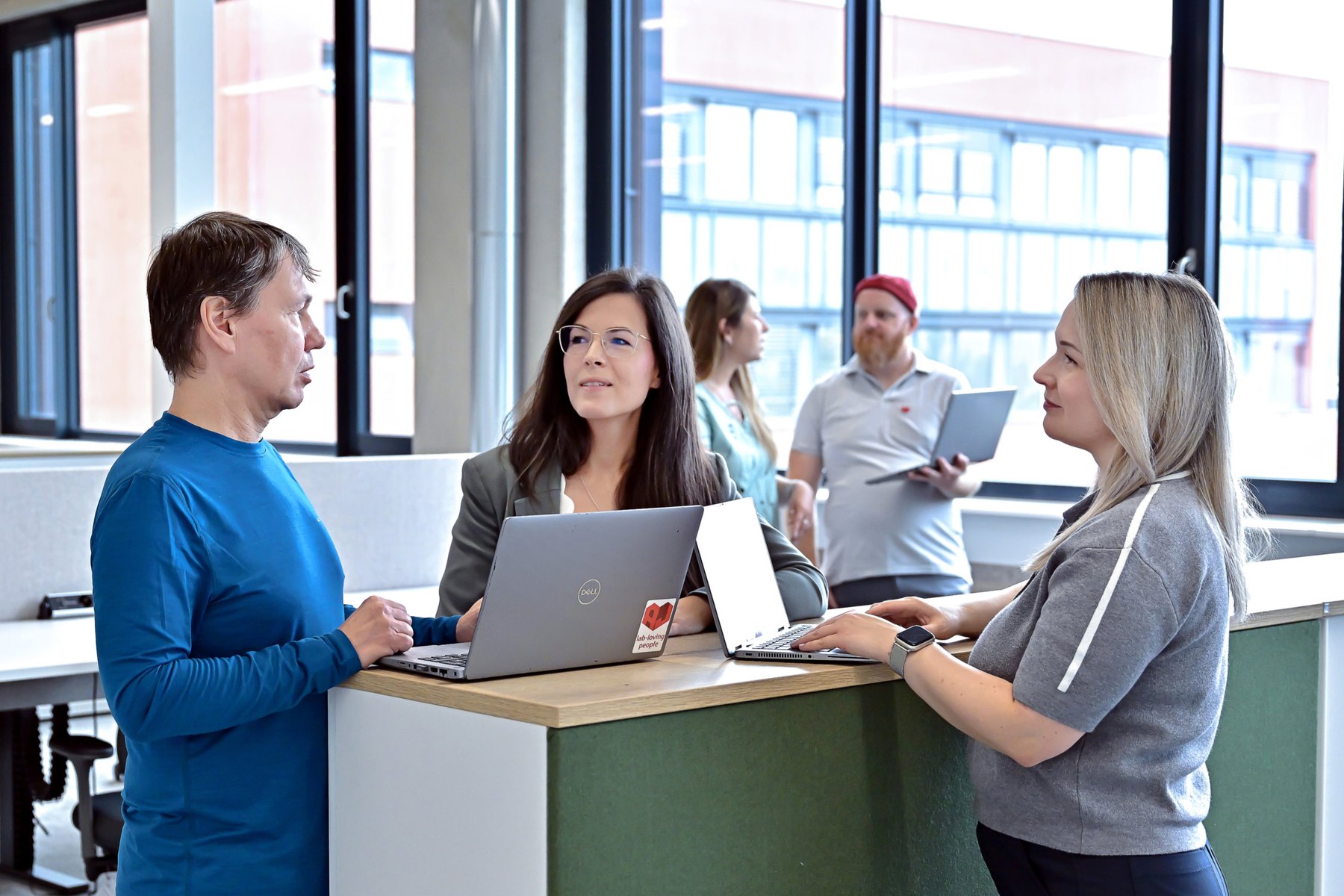 Employees talking at a standing desk with laptops in the new office at the Analytik Jena site in Jena
