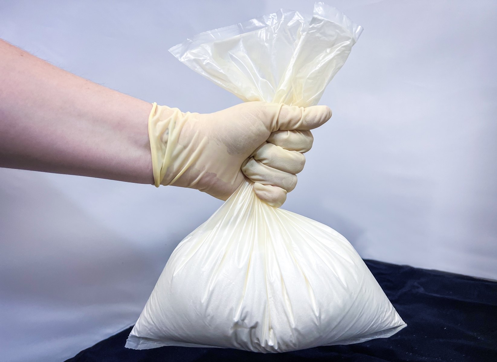 Gloved hand holding a water-soluble pouch of Cortec corrosion inhibitor powder for boiler and cooling system layup and startup