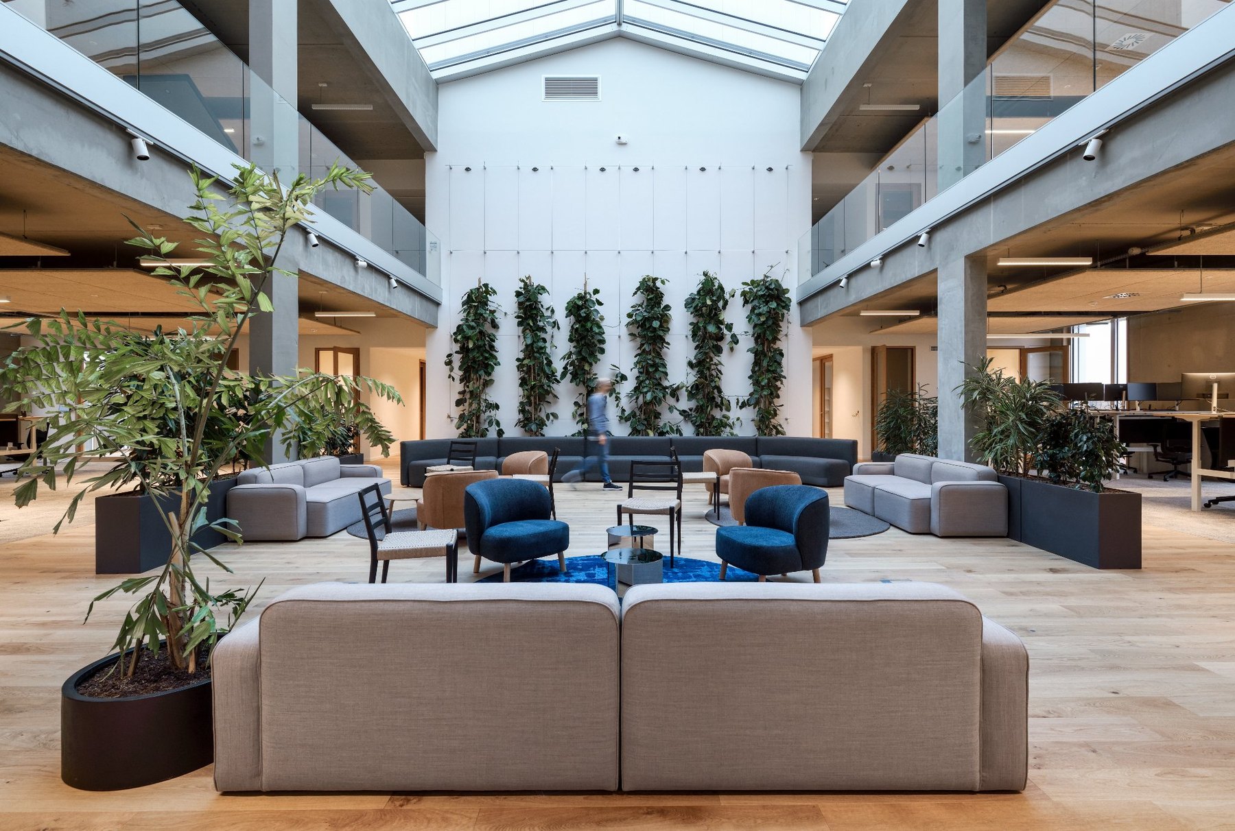 Open breakout area with sofas, armchairs and plants under a glass roof in the new Endress+Hauser building in Cernay