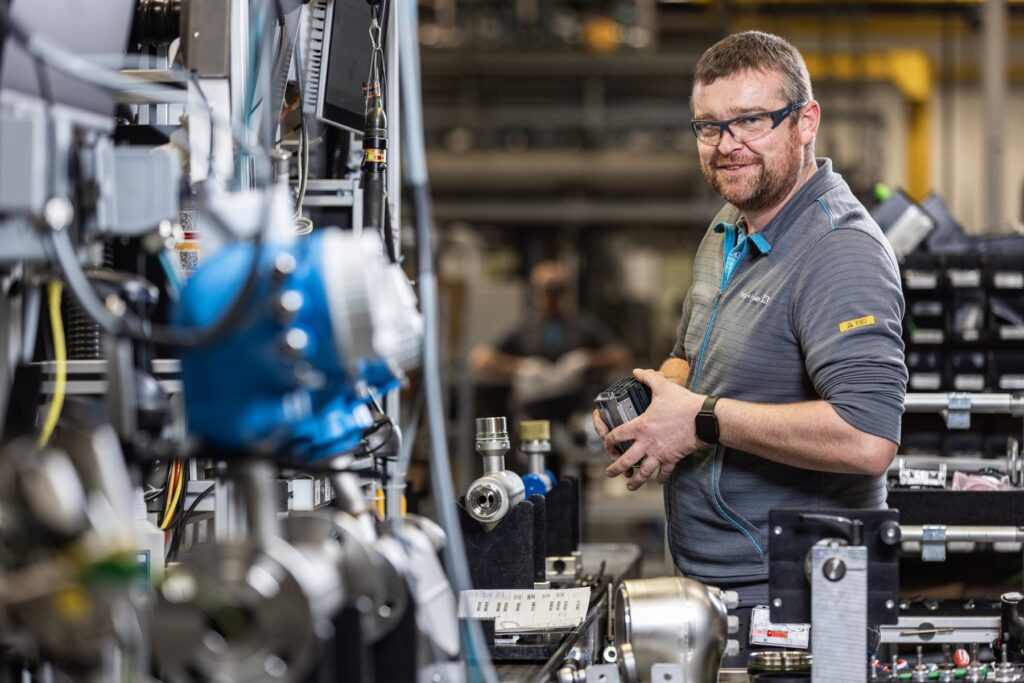 Endress+Hauser employee holding a measurement instrument component in the flowmeter production hall
