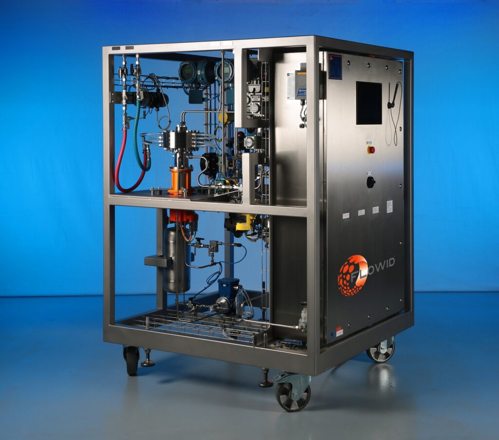 Skid-mounted Flowid SpinPro unit for industrial use with reactor, pumps, instrumentation and control cabinet in a stainless steel frame