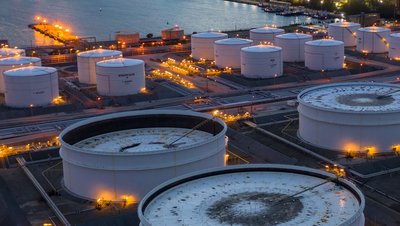 Tank farm with round storage tanks lit up at dusk