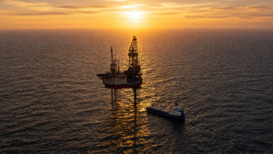 Offshore platform and supply vessel at sea during sunset