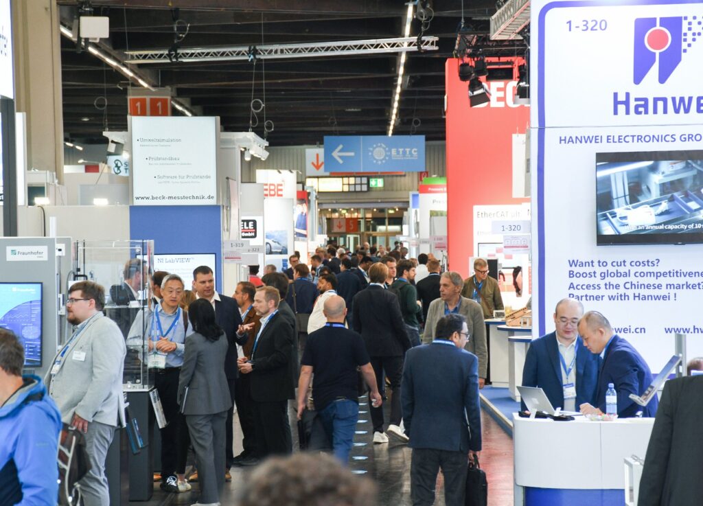Visitors walking the aisles between exhibitor stands in an exhibition hall at SENSOR+TEST in Nuremberg