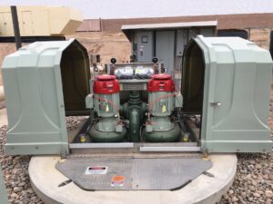 Above-ground wastewater pump station with two pumps and controls inside an open fiberglass enclosure on top of a wet well