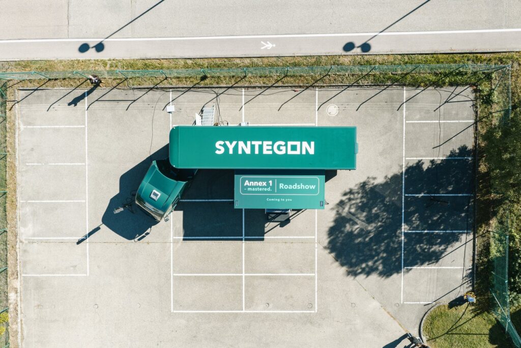 Aerial view of the green Syntegon truck with the Annex 1 Roadshow lettering on its extended trailer roof