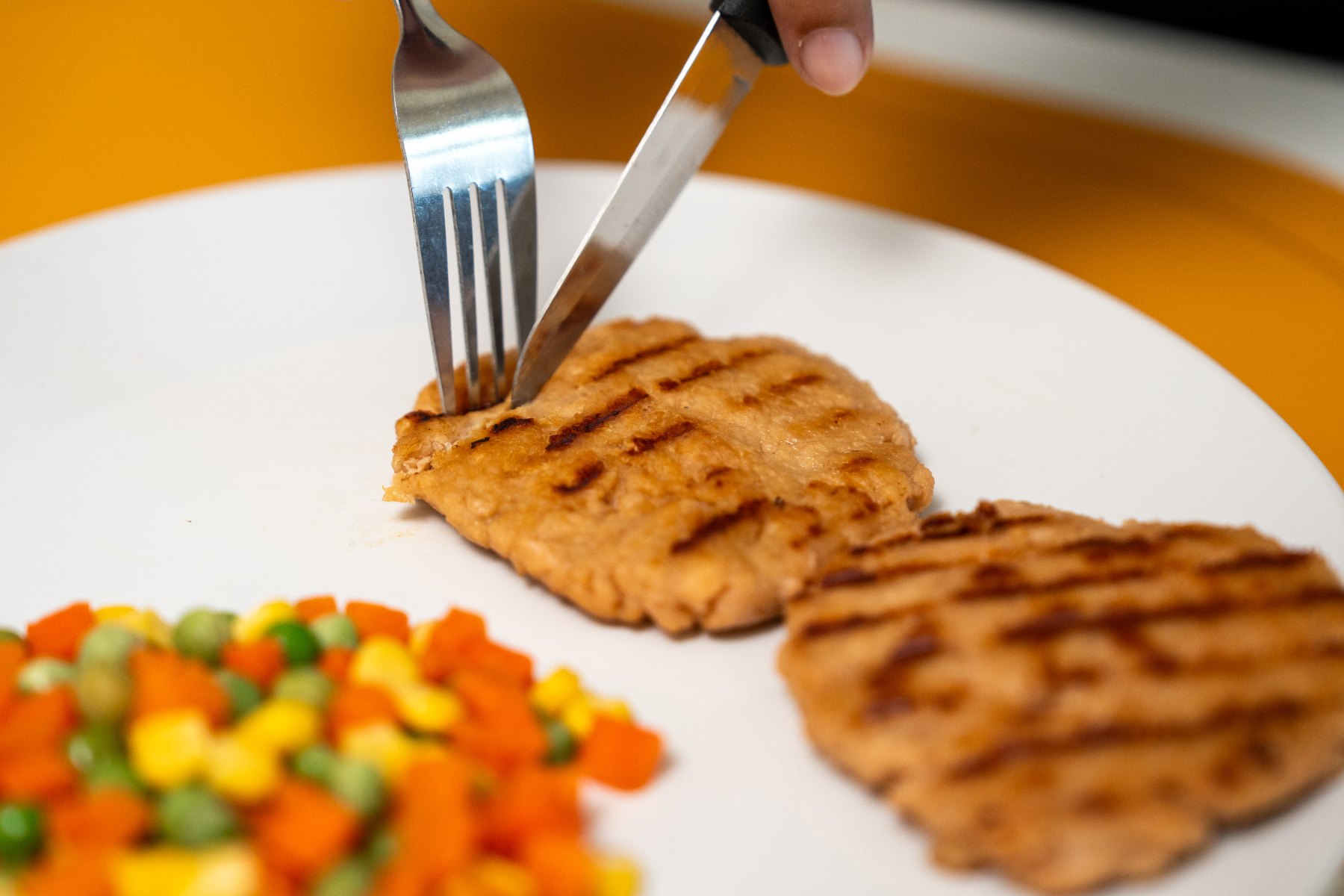 Grilled meat replacement patty served with mixed vegetables, an example of an ultra-processed food perceived as healthy